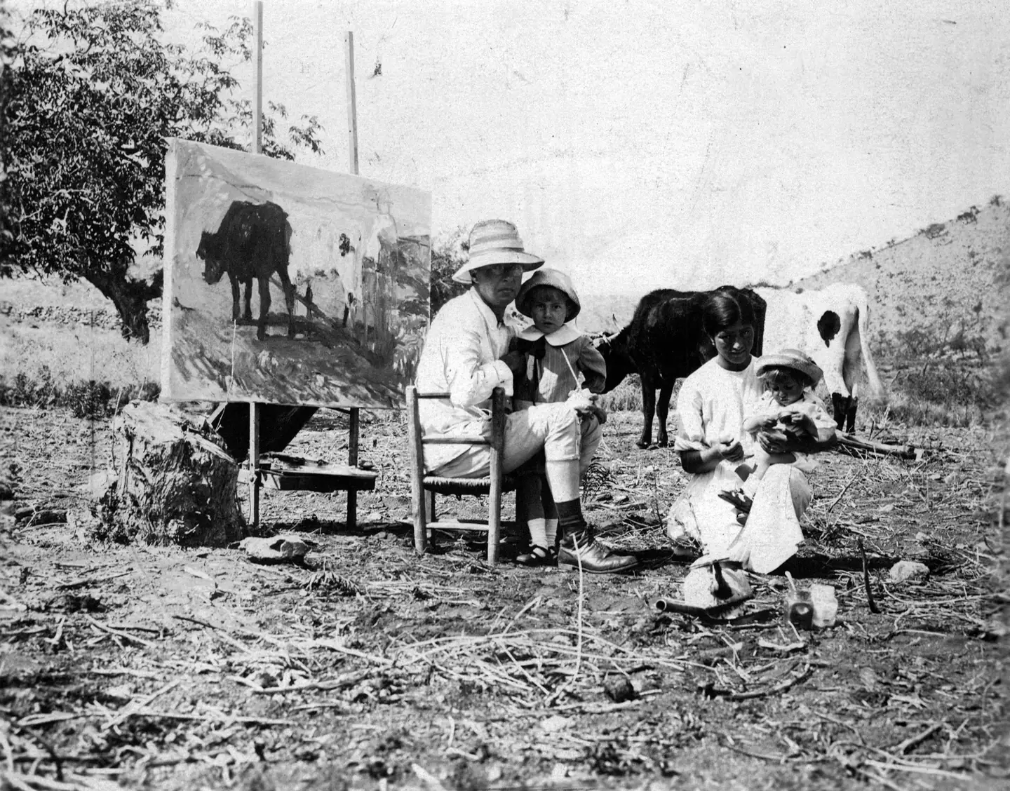 Fader sentado ante el caballete, en el campo, con una vaca de modelo