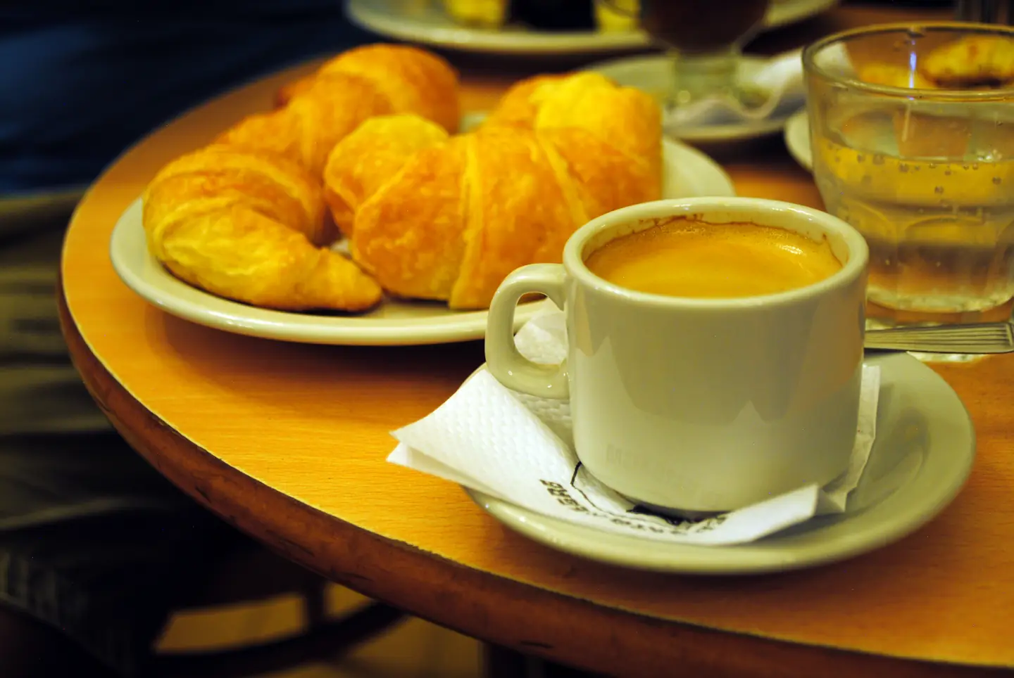 Jarrito, dos medialunas y un vaso de agua en una mesa de madera