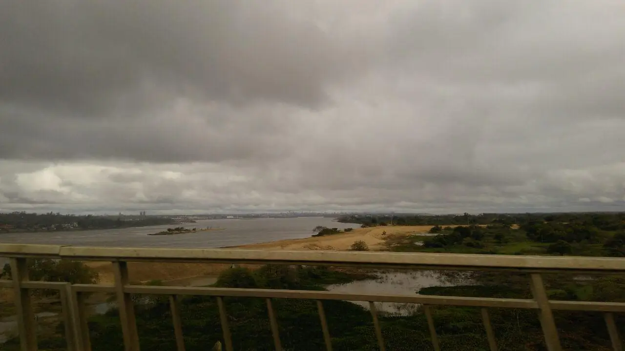 El río Paraguay desde la baranda de un puente, con el cielo cubierto